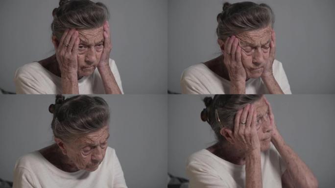 在家头痛的高级女性。带着皱纹和白发的老奶奶抱着头高血压和偏头痛寻求帮助。医疗保健概念。有痛苦的感觉偏