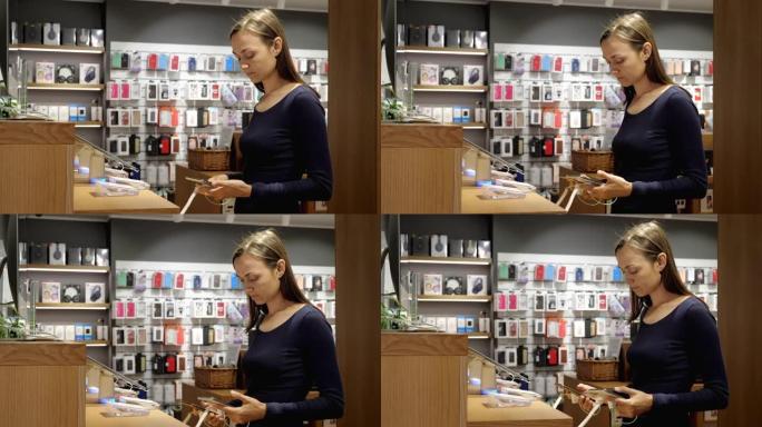 年轻女子在一家电子商店选择一款新的智能手机。