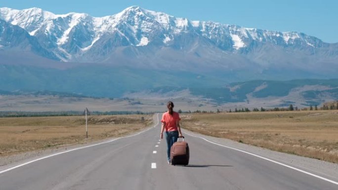 女人带着手提箱在山路上旅行