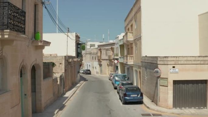 地中海小镇的空旷街道，因为冠状病毒19大流行和封锁，空中移动车在米色和沙色房屋之间前进
