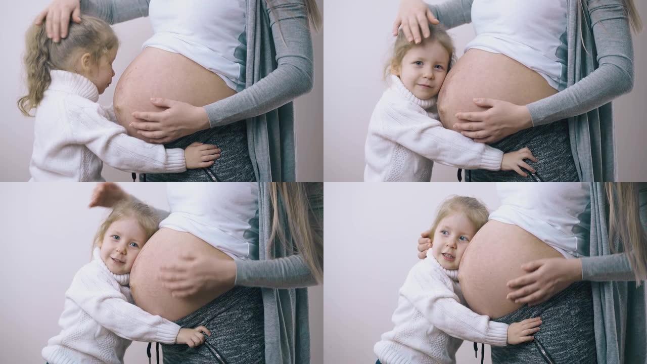 小孩拥抱怀孕的妈妈在白墙露出肚子