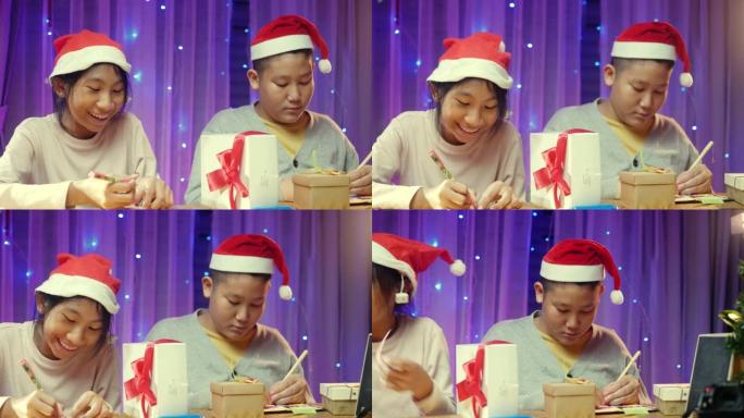 快乐的亚洲孩子戴着圣诞老人的帽子，为圣诞灯背景的家庭派对准备礼品盒和贺卡。