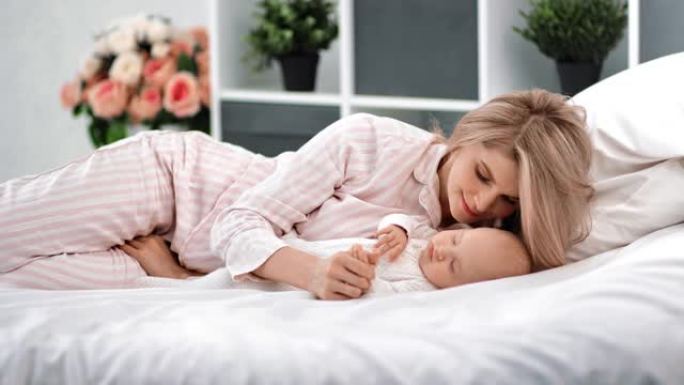 穿着睡衣的好女人看着熟睡的孩子享受快乐的母亲。4k龙红相机