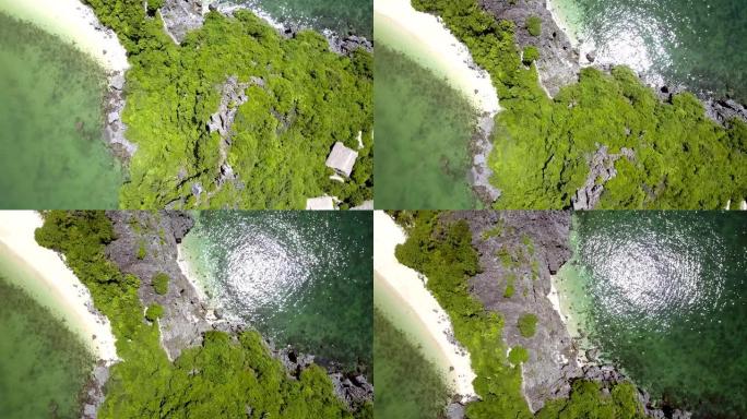 无人机在沙滩上沿着绿色的岩石岛飞行