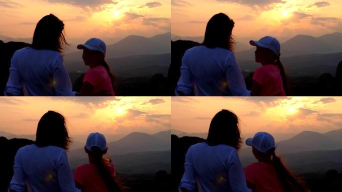 在山里日落的背景下，一个女人和一个十几岁的女孩的轮廓。游客在夏天欣赏希腊梅泰那山的日落