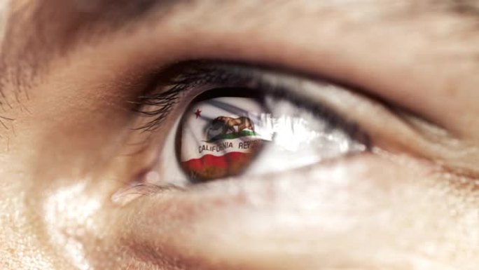 近距离看，褐色眼睛的人，虹膜色的加州国旗，随风飘扬的美利坚合众国。视频的概念