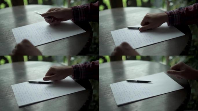 Kuchl/奥地利-2019年8月22日: 男人写信，把笔放在靠近白纸的木桌上。复古字母婚礼爱情故事