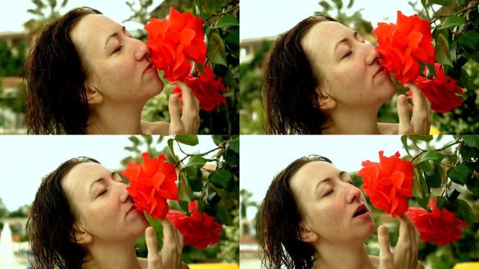 漂亮的女人嗅着红色盛开的玫瑰花蕾。希腊。慢动作。高清