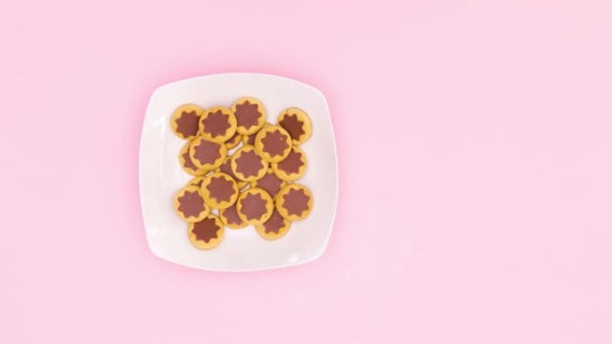 巧克力饼干填充白色盘子和牛奶填充粉色主题的粉色杯子，手拿一个饼干和牛奶。停止运动