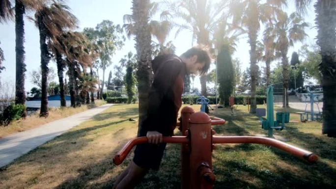 一个年轻人在公园里做双杠浸入运动以热身三头肌的实时视频拍摄