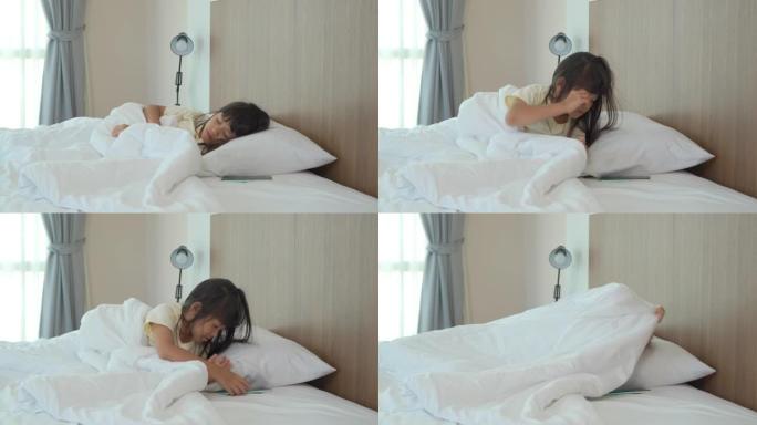 睡在家里床上的亚洲女学生醒来，禁用躺在床头柜上的手机触发的闹钟，转身睡在毯子里。