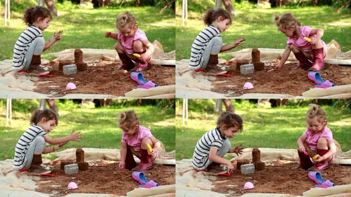 两个小女孩在后院的沙箱里玩耍