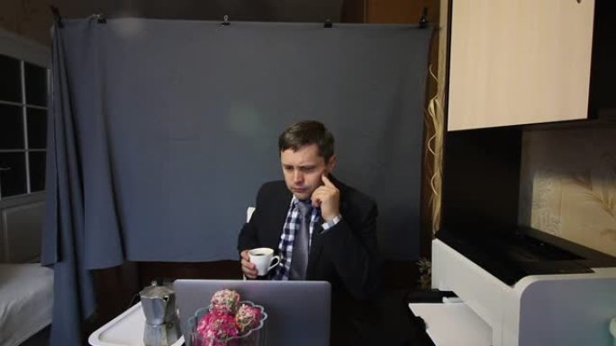 视频通话时吃东西。一个穿着西装的男人正在通过视频交流交谈。交流时，他喝咖啡和手势。