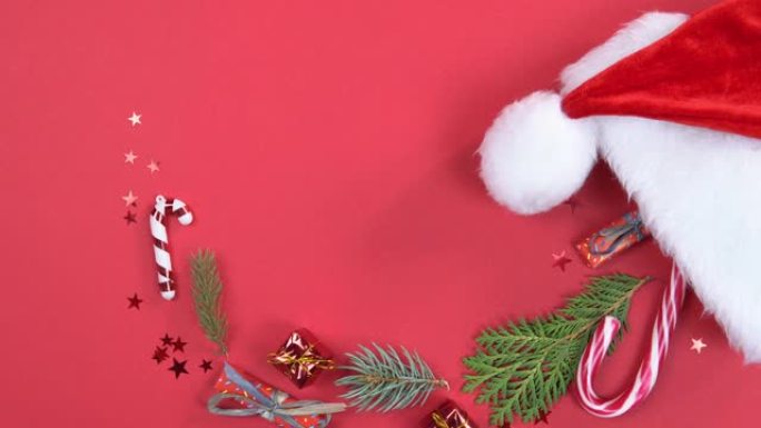 圣诞背景360度旋转。带有装饰的圣诞老人帽子和红色背景上旋转的杉木树枝