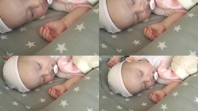 可爱的两个月大的新生高加索女婴甜蜜地用奶嘴睡觉，拥抱毛绒泰迪熊