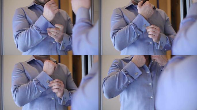 一个穿着蓝色衬衫的男人将袖扣固定在衬衫上