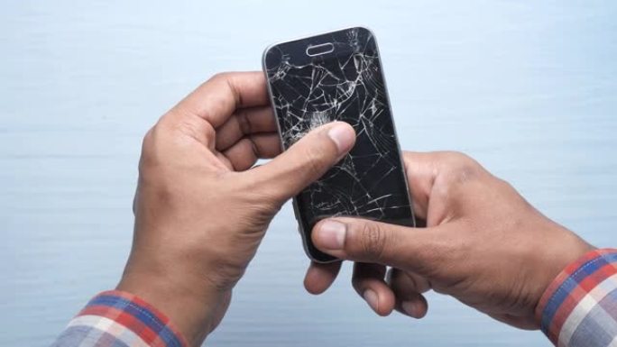 男子手持破碎智能手机的特写。