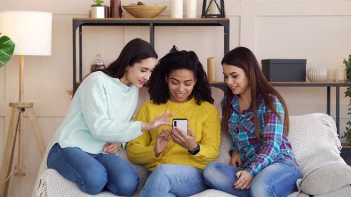 和蔼可亲的多种族女孩在家使用智能手机浏览社交媒体