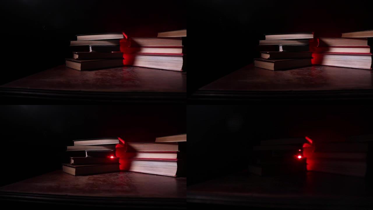 一堆旧书。木制桌子上的老式书籍。黑暗房间里发光的书周围有神奇的闪电。选择性聚焦