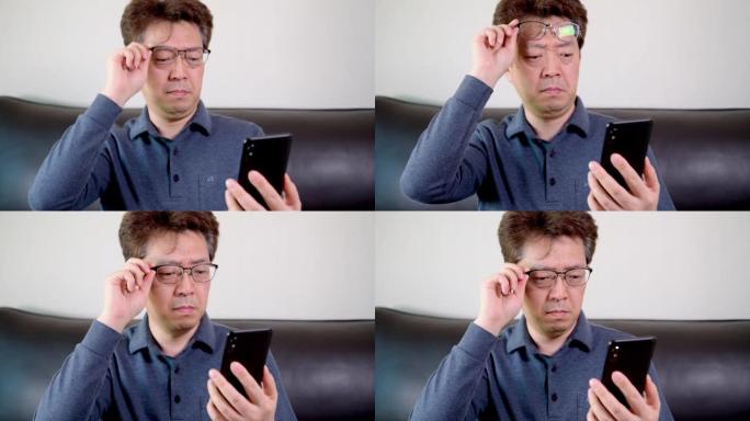 亚洲中年男性试图在手机上阅读一些东西。老花眼，近视。