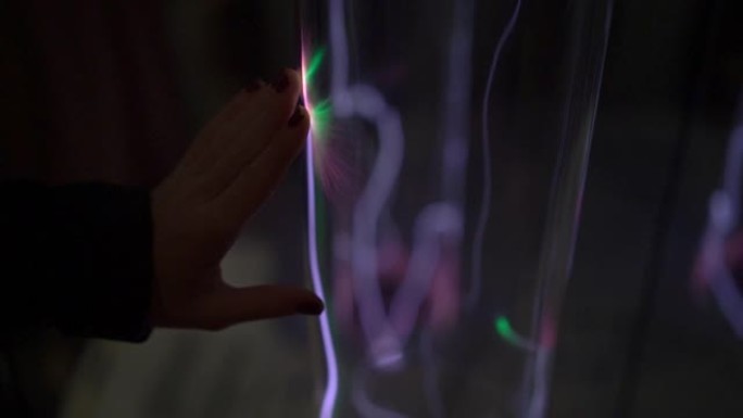 安装在科学博物馆。一个女人的手用发光的气体将管子伸出来的慢动作镜头。惰性气体发光。带有发光等离子体的