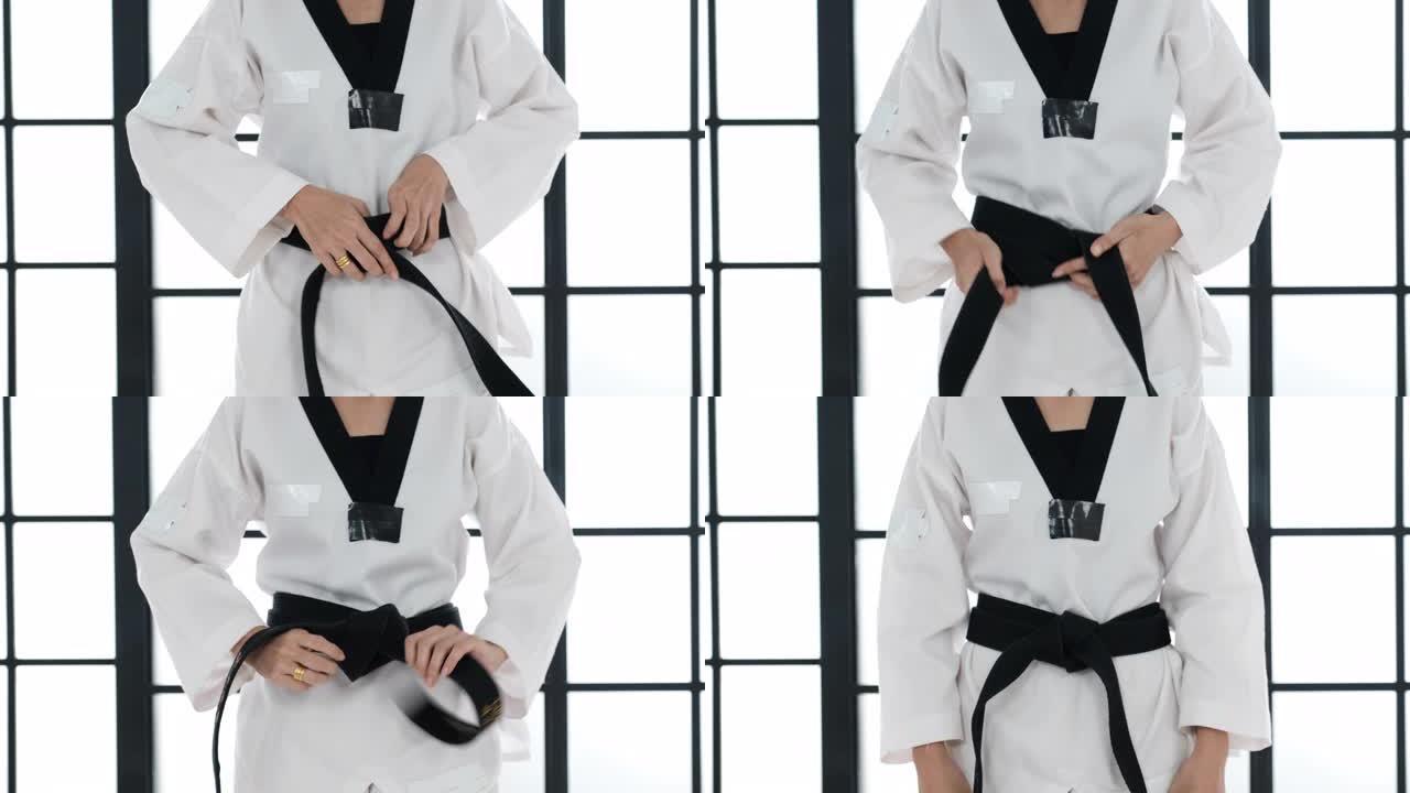 跆拳道女孩的特写镜头在白色房间里把黑带绑在她的裙子上。腰带上显示的文字是跆拳道的意思。