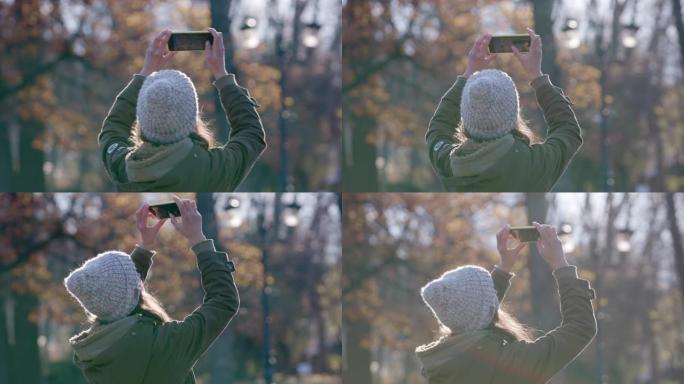 带着手机摄像头的年轻女子在森林里拍照