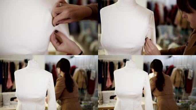 将袖子固定在未来的白色连衣裙或西装上的过程的特写。女裁缝在模特上的袖子上。专业工作室的镜头模糊，背景