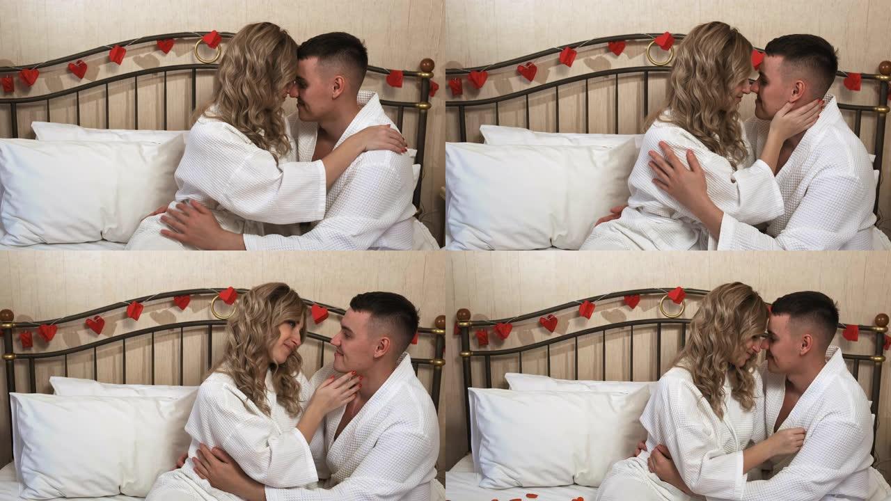 床上穿着浴袍的情侣拥抱微笑。