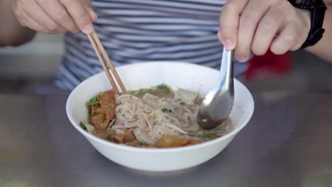 亚洲男子吃泰国猪肉面条加汤。