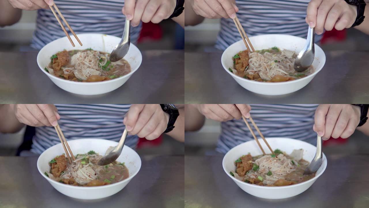 亚洲男子吃泰国猪肉面条加汤。