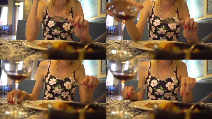 烤土豆、肉、西红柿、莳萝。在餐馆桌子上的盘子里。在一杯酒的背景下，一个女人吃东西，