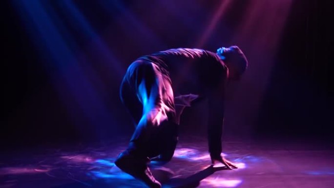 专业霹雳舞和嘻哈舞者的轮廓在聚光灯下在地板上旋转。特写。慢动作