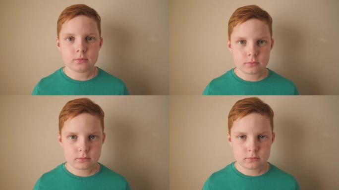 室内严肃的红头发雀斑小男孩的肖像。不高兴的小姜黄色的孩子看着里面的相机。闭上情绪的男孩与悲伤的表情在