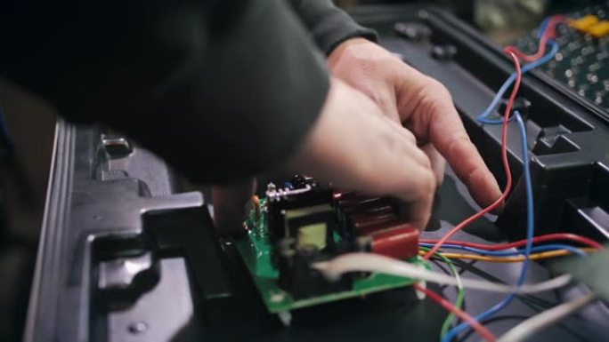 工人在生产现场连接红绿灯的芯片。特写。发光二极管矩阵、光块、节能交通灯、电线、电子。交通信号灯的维修