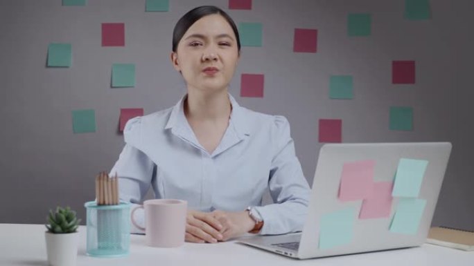 坐在家庭办公室的笔记本电脑上工作的亚洲妇女因鼻塞而喘不过气来。