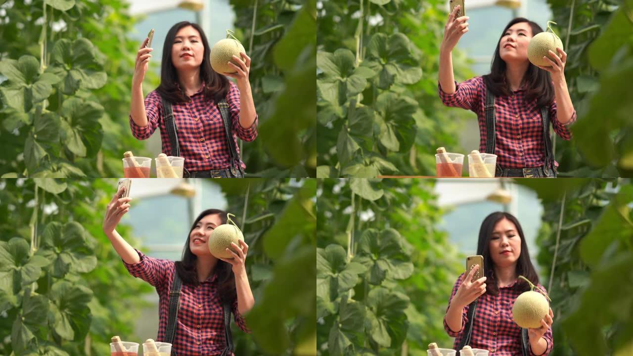在oganic蔬菜农场工作的亚洲年轻女农民，转基因食品，生物食品概念，使用智能手机进行电子商务