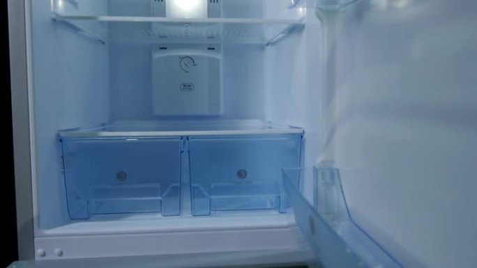 相机沿着带有塑料盒架子和灯的冰箱移动
