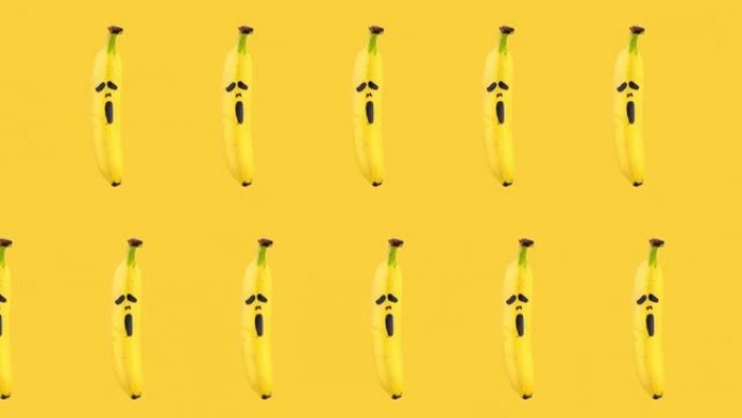 两排香蕉的无缝循环动画，上面画着黄色背景上可怕的恐惧面具。万圣节概念与复制空间