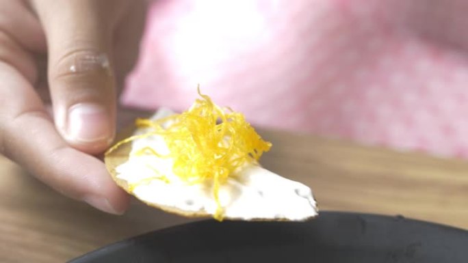 亚洲女孩在吃前将黄油奶油涂在甜零食上，生活方式理念。
