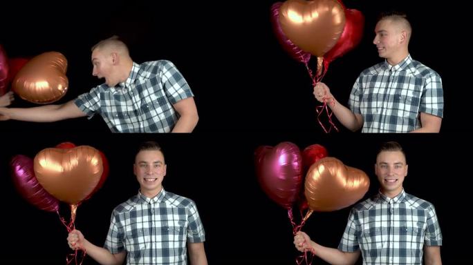 心形气球被赠送给一个年轻人。该名男子感到惊讶，将手中的氦气气球放在黑色背景上。情人节是情人的日子。