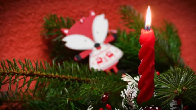 以红色蜡烛为重点的架子，上面点着圣诞装饰和绿色杉木树枝。