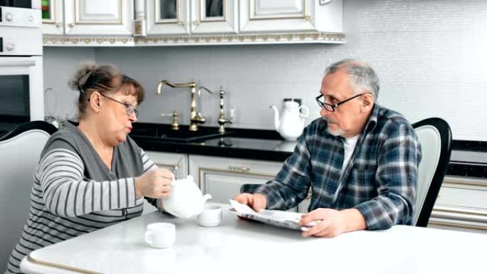 成熟的女性从茶壶中倒茶，在舒适的厨房与丈夫交谈