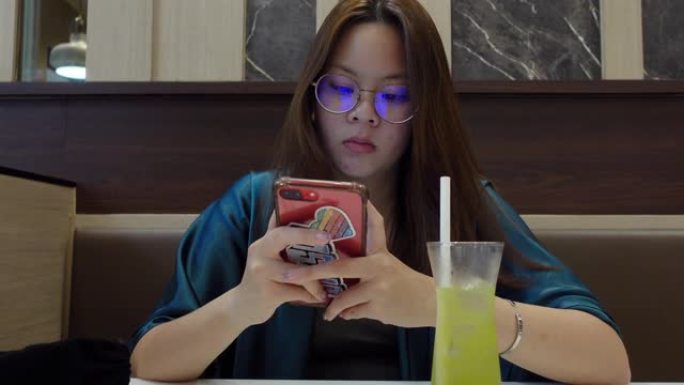 年轻女子在吃东西时使用智能手机，Nomophobia概念