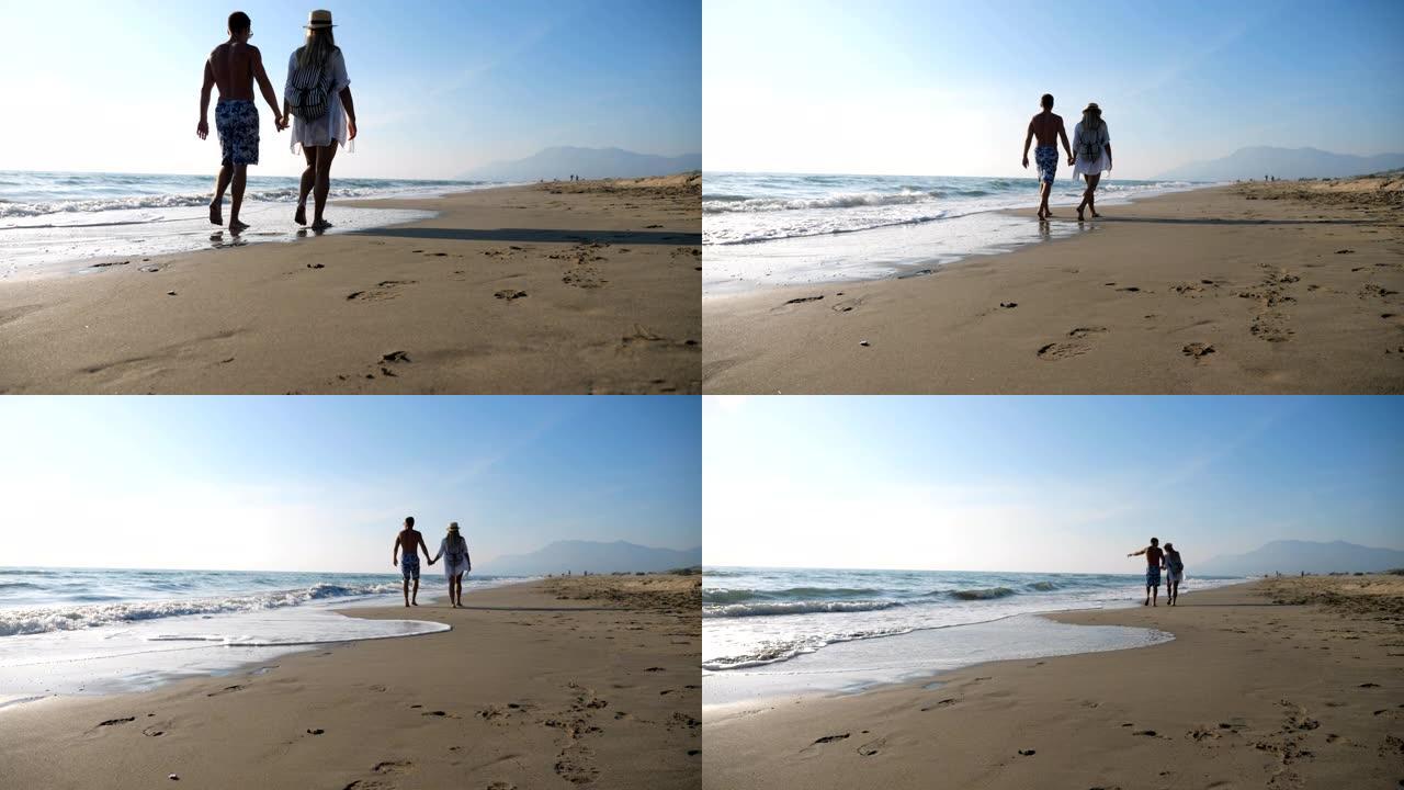 情侣在度假胜地休闲时牵手走在海边。男人和女人在海滩上漫步，享受暑假。年轻一对的蜜月。爱和幸福的概念。