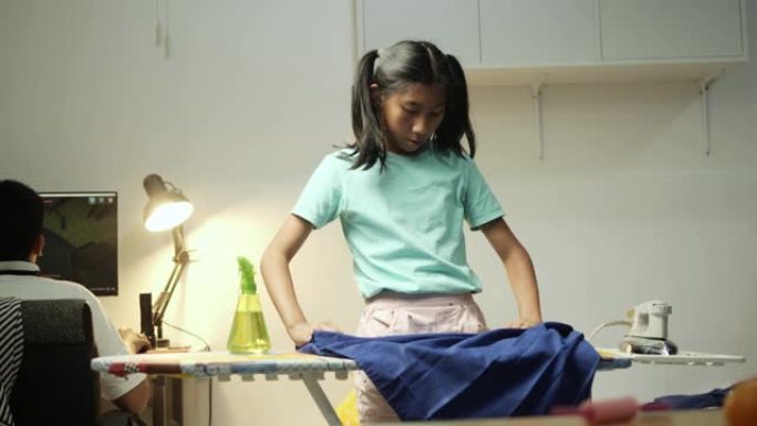 亚洲女孩晚上在家熨烫学生服。