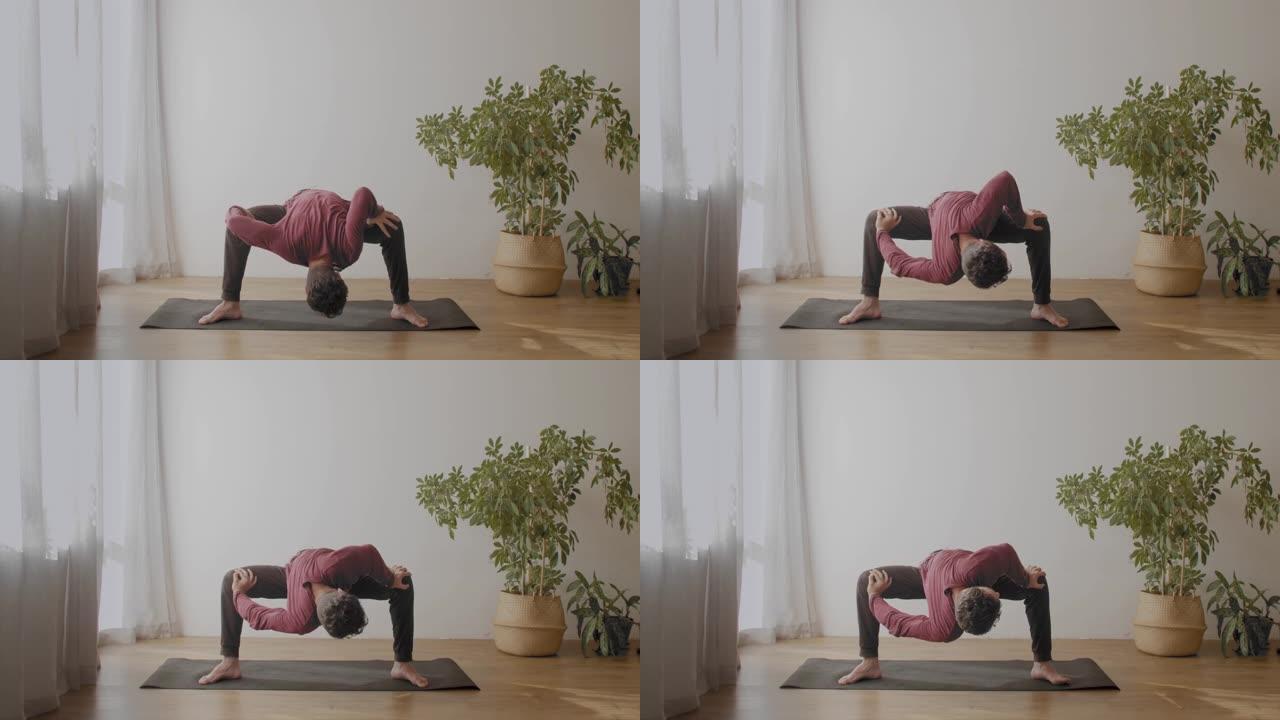 柔韧的男人做瑜伽室内阳光房背景慢动作。瑜伽大师站在平衡体式伸展腿部肌肉复制文本空间。健康生活方式身体