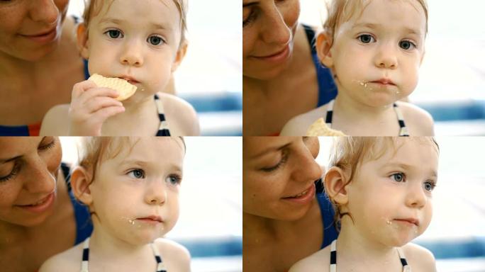 这孩子吃饼干。在游泳池里吃饭后的孩子吃饼干。