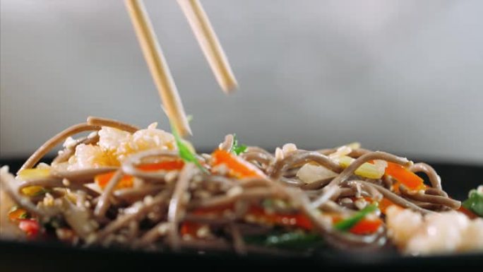 用筷子吃传统的亚洲荞麦面和虾炒面