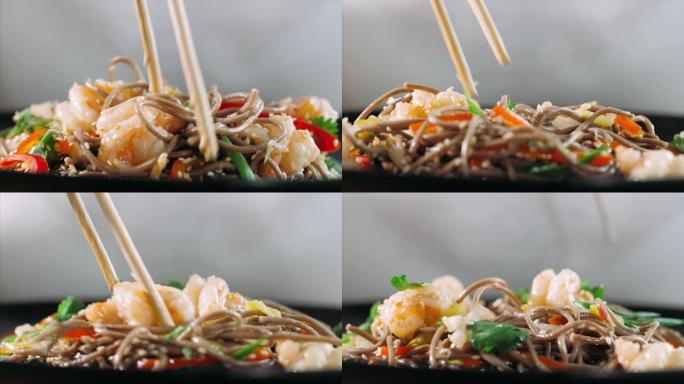 用筷子吃传统的亚洲荞麦面和虾炒面